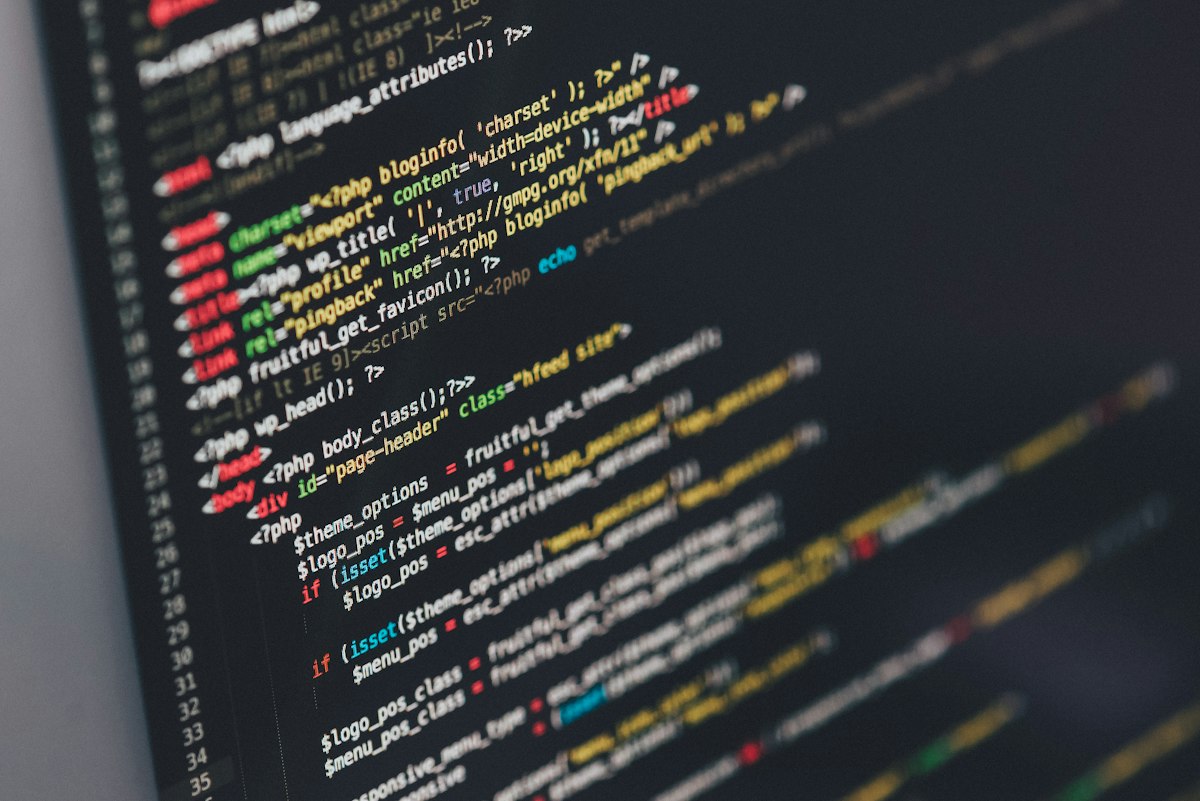 Desenvolvedor escrevendo código de sistema sob medida em dois monitores